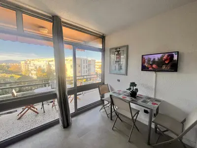 a dining room with a table and a large window at Heliotel Marine Studio 30m2 très lumineux avec terrasse 17m2 au 3eme étage in Saint-Laurent-du-Var