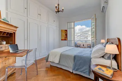 a bedroom with a bed and a desk with a laptop at Elegant Condo with Balconies in the Heart of Nice in Nice