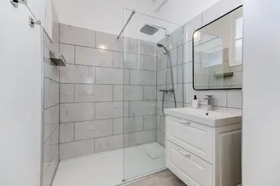 a white bathroom with a shower and a sink at Elegant Condo with Balconies in the Heart of Nice in Nice
