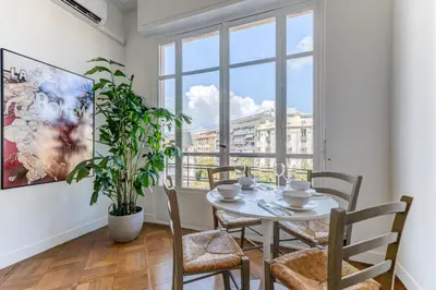 a dining room with a table and chairs and a window at Elegant Condo with Balconies in the Heart of Nice in Nice