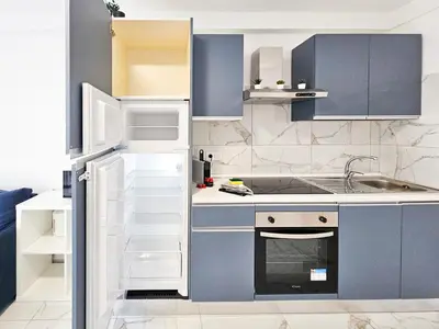a small kitchen with blue cabinets and a sink at New Big Flat 8 Pers AC WiFi in Nice