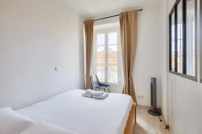 a bedroom with a bed and a chair and a window at Lovely 1 BR Flat in the heart of Nice in Nice