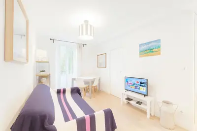 a white bedroom with a bed and a tv at Cassini 2 Pers Hyper Center WiFi in Nice