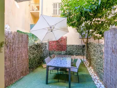 a table and chairs with an umbrella in a courtyard at Chateau 4 Pers Vecchia Nizza AC WiFi in Nice