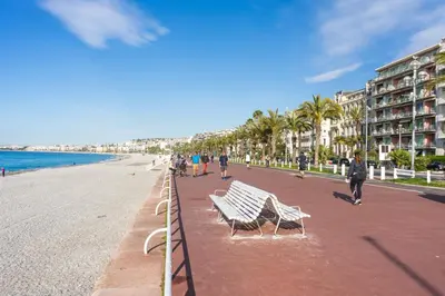 a group of benches on a beach with buildings at Promenade 2 Pers Vista Mare WiFi AC in Nice