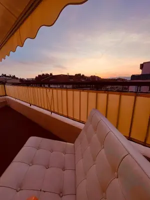 a couch on a balcony with the sunset in the background at Penthouse avec terrasses panoramiques in Nice