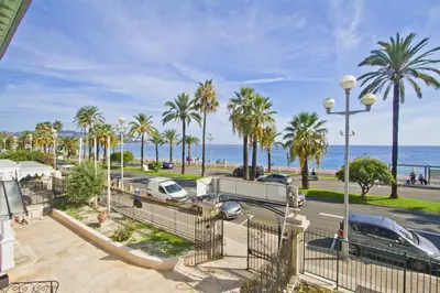 a view of a street with palm trees and the ocean at Cosy Cariatides Condo Promenade in Nice