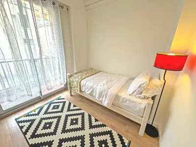 a small bedroom with a bed and a red lamp at Cosy Cariatides Condo Promenade in Nice