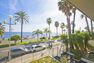 a view of a street with palm trees and the ocean at Cosy Cariatides Condo Promenade in Nice