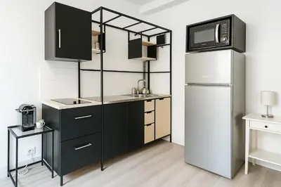 a kitchen with black cabinets and a white refrigerator at Stella Monte 2 AC WiFi 2 Pers in Nice