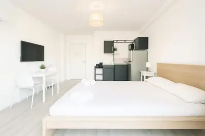 a white bedroom with a large bed and a kitchen at Stella Monte 2 AC WiFi 2 Pers in Nice