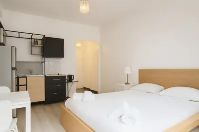 a bedroom with a large white bed and a kitchen at Stella Monte 3 AC WiFi 2 Pers in Nice