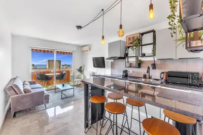 a kitchen and living room with a counter and stools at Bel appartement vue mer proche de la promenade des anglais in Nice