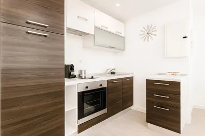a kitchen with white and wood cabinets and a sink at Massena 4 Pers Super Centrale WiFi AC in Nice