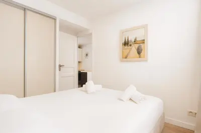 a white bedroom with two beds and a painting on the wall at Massena 4 Pers Super Centrale WiFi AC in Nice