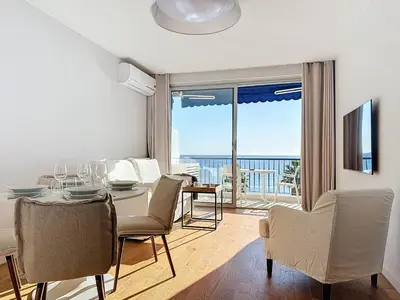 a dining room with a table and chairs and a balcony at Seaview Promenade des Anglais 2brs apartment Parking cars 1800 kg max in Nice