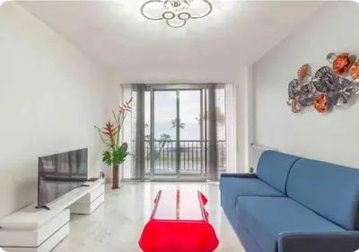 a living room with a blue couch and a table at Nice promenade des anglais vue mer in Nice