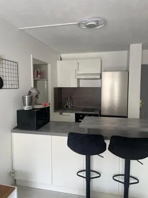 a kitchen with white cabinets and two black bar stools at Le soleil Niçois, proche du port in Nice