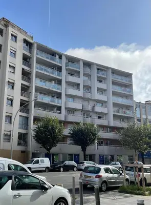 an apartment building with cars parked in a parking lot at Le soleil Niçois, proche du port in Nice