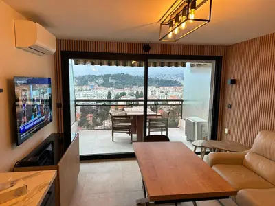 a living room with a couch and a television and a table at L'évidence in Nice