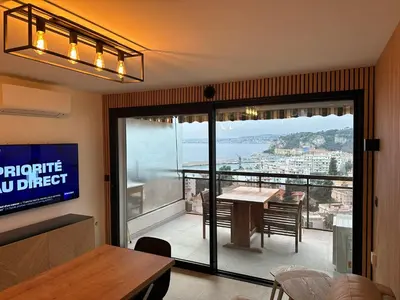 a room with a table and a balcony with a view at L'évidence in Nice