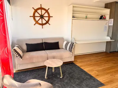 a living room with a couch and a table at Heliotel Marine Studio avec balcon au 4eme étage à 200m de la mer in Saint-Laurent-du-Var
