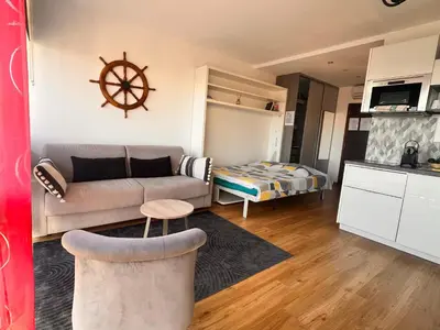 a small living room with a couch and a kitchen at Heliotel Marine Studio avec balcon au 4eme étage à 200m de la mer in Saint-Laurent-du-Var