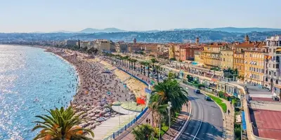 a city with a beach and the ocean and buildings at blue sun in Nice
