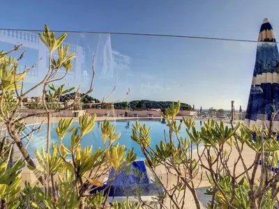 a view of a swimming pool with an umbrella at Riviera-King-Studio in Villefranche-sur-Mer