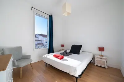 a bedroom with a bed and a chair and a window at Cosy 3P en plein cœur de Nice in Nice