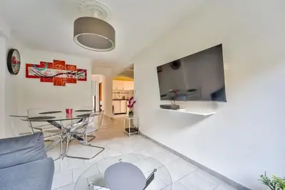 a living room with a table and a tv on a wall at Modern 2BR Flat - Haut de Nice in Nice