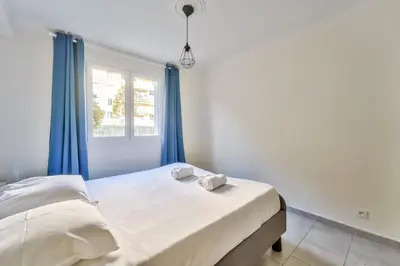 a bedroom with a bed with blue curtains and a window at Modern 2BR Flat - Haut de Nice in Nice