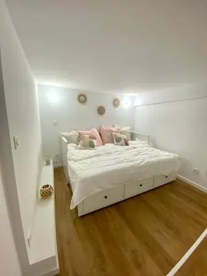 a white bedroom with a bed with pink pillows at Studio cosy Nice in Nice