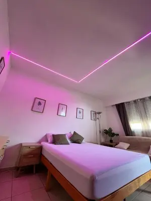 a bedroom with a bed with a pink light on the ceiling at Terrasse, piscine, clim, proche aéroport et plage in Saint-Laurent-du-Var