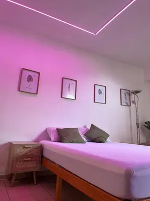 a bedroom with a bed with pink lighting at Terrasse, piscine, clim, proche aéroport et plage in Saint-Laurent-du-Var