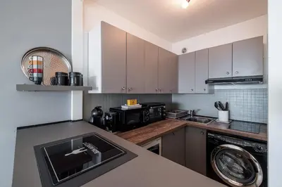 a kitchen with white cabinets and a black appliance at Sea View & Promenade des Anglais Studio in Nice