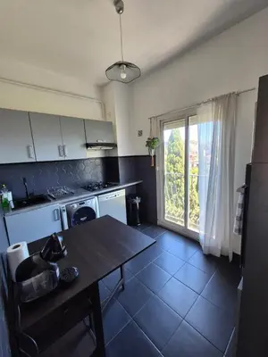 a kitchen with a table and a large window at Appartement à 2 pas de la Promenade des Anglais vue mer 7 avenue de Fabron in Nice