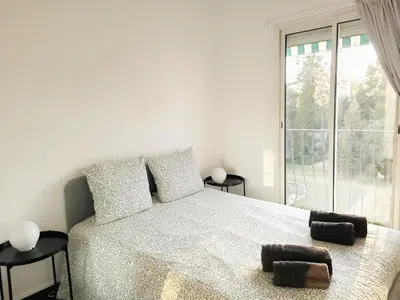 a white bedroom with a bed and a large window at Appartement à 2 pas de la Promenade des Anglais vue mer 7 avenue de Fabron in Nice