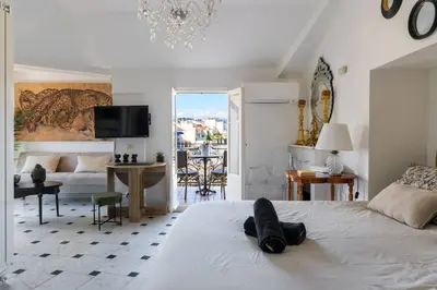 a bedroom with a white bed and a living room at Perchoir au coeur de Nice in Nice