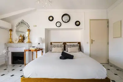 a bedroom with a large white bed and clocks on the wall at Perchoir au coeur de Nice in Nice