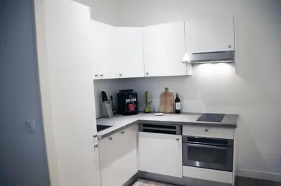 a white kitchen with white cabinets and appliances at Apartment Massena in Nice