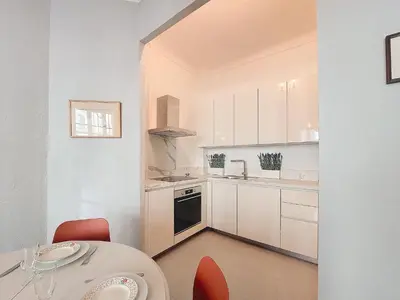 a kitchen with white cabinets and a table with red chairs at Nestor&Jeeves - ORANGE - Central - Near Sea in Nice