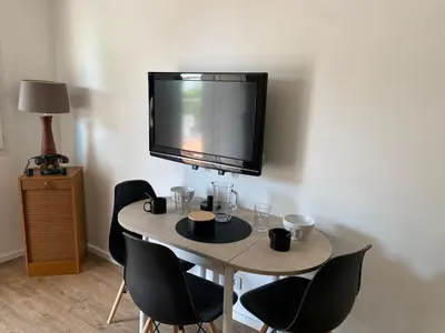 a small table with chairs and a television on a wall at Rez de Jardin Villa Cagnes Sur Mer. in Cagnes-sur-Mer