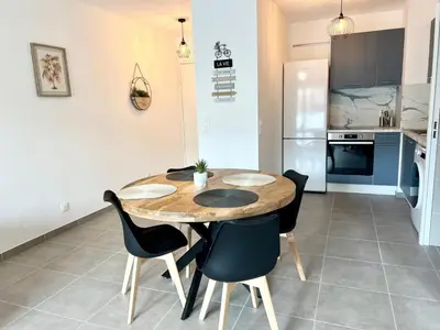 a kitchen with a wooden table and chairs in a room at Brand new flat with terrace and parc view in Nice