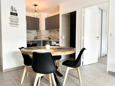 a kitchen with a wooden table and black chairs at Brand new flat with terrace and parc view in Nice
