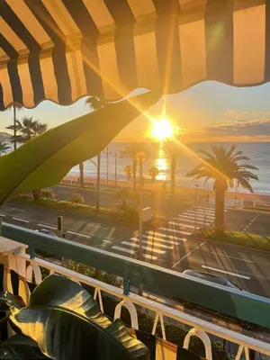 a view of the beach and the ocean at sunset at Nice Promenade des Anglais Your Seafront Flat in Nice