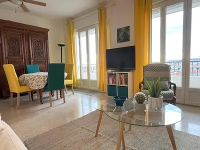 a living room with a table and chairs and a tv at Terrace and view on all Nice city in Nice