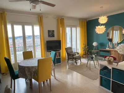 a living room with a table and chairs and a television at Terrace and view on all Nice city in Nice