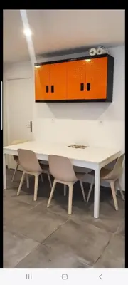 a dining room table with chairs and an orange cabinet at Grand Appartement 5 chambres, 5 télévision , 95 m2, vue mer, tramway sur place, gare train 2 min, aéroport 5 min , Large Apartment 5 bedrooms, 5 televisions, 95 m2, sea view, tram on site, train station 2 mins, airport 5 mins in Nice