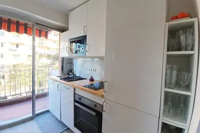 a kitchen with white cabinets and a large window at 2-rooms apartment with Wifi and balcony in Nice